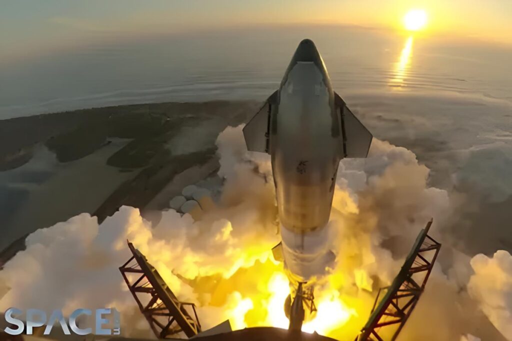 A rocket launches at sunrise over a coastal area, with flames and smoke billowing from its engines. The sun is low on the horizon, reflecting on the water. The word SPACE is visible in the lower left corner.